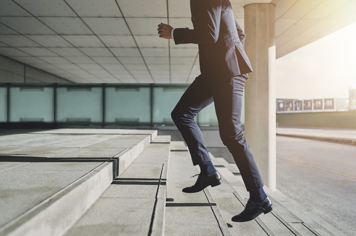 Man in suit walking up the stairs of building entrance with large windows