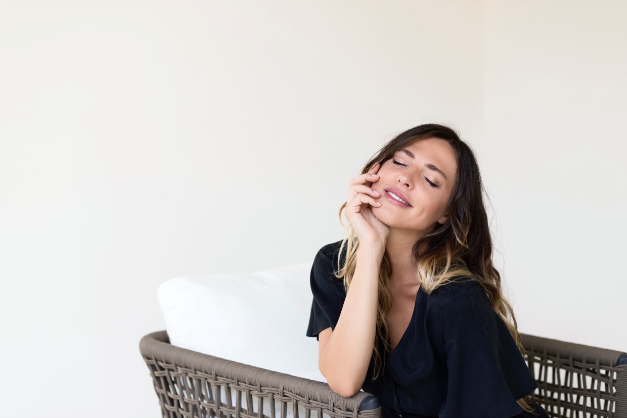 Woman resting her head on her hand while smiling in a softly lit setting